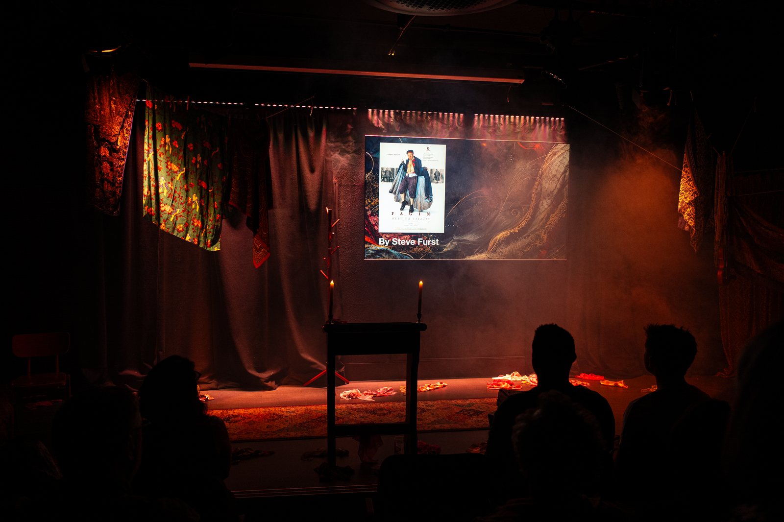 The Circle & Star stage during Fagin, candlelit, draped costumes, audience in silhouette