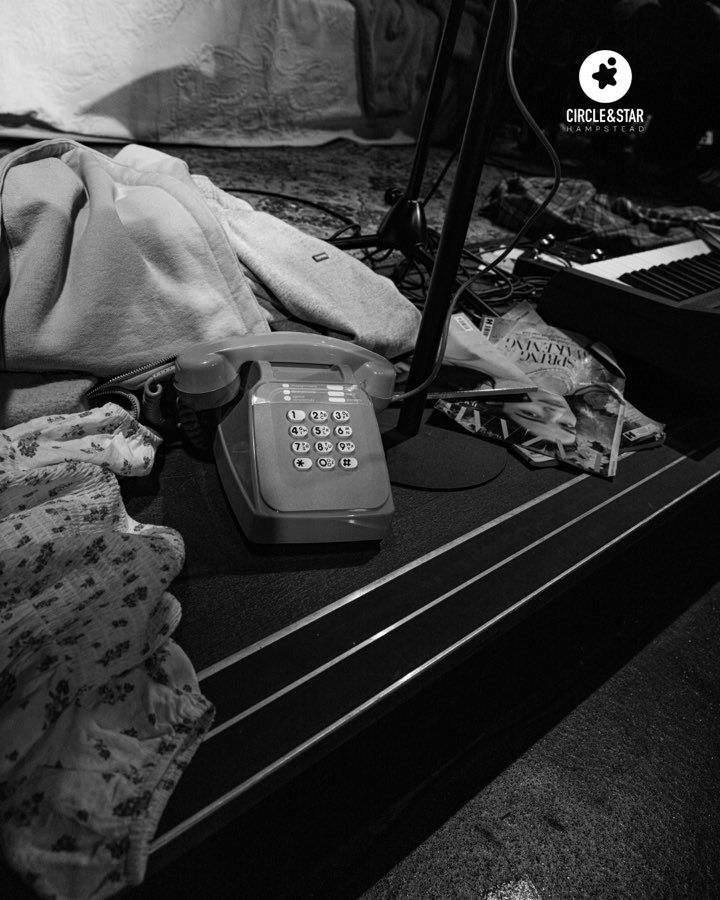 A prop telephone and scattered clothes on the edge of the stage